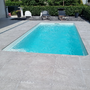 Piscina esterna con pavimentazione in granito e arredi